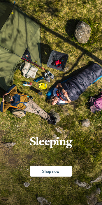Couple resting outside the tent in the nature in a camping chair and inside the sleeping bag